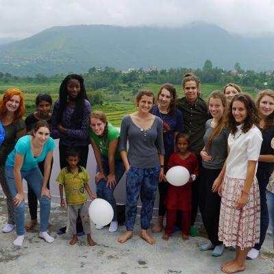 Projects Abroad high school student volunteers doing construction work in Nepal take a photo with local children at their placement. High school student volunteers doing building work in Nepal pose for a photo with young children and locals.